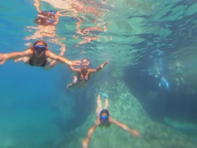 Drei Personen beim Schnorcheln unter Wasser in klarem türkisfarbenem Meerwasser