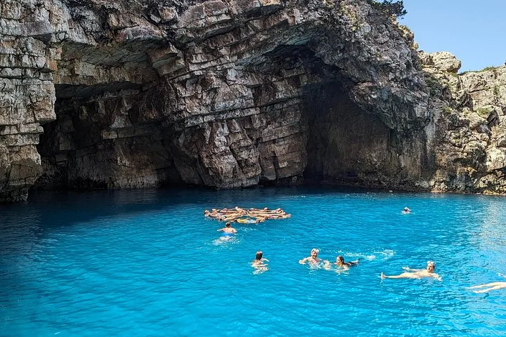 Gruppe von Menschen, die in einem atemberaubend blauen Meer nahe einer felsigen Klippe schwimmen