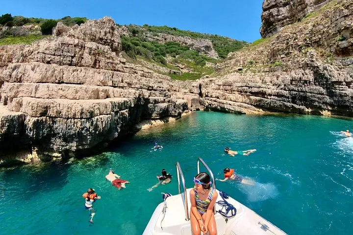 Touristen beim Schwimmen und Schnorcheln in einer kleinen felsigen Bucht mit klarem Wasser