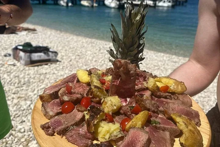 Una fuente de carne a la parrilla y patatas en un entorno de playa